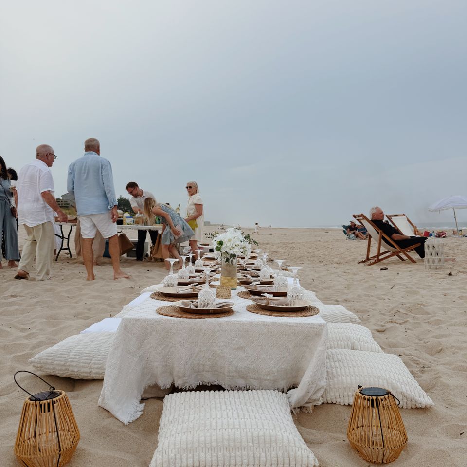 Beachside low table with white linens and floor cushions styled for a family gathering in the Hamptons