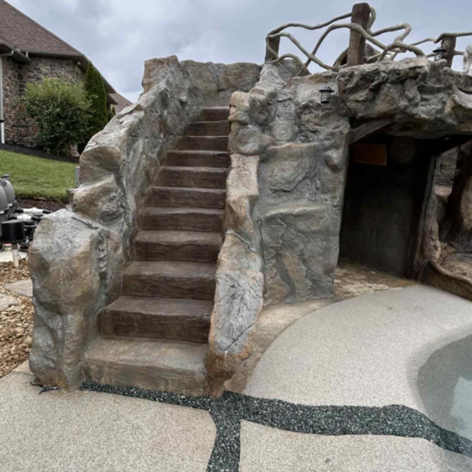 ClifRock Outdoor pool feature with rock-textured steps, cave-like opening, and concrete pool deck.