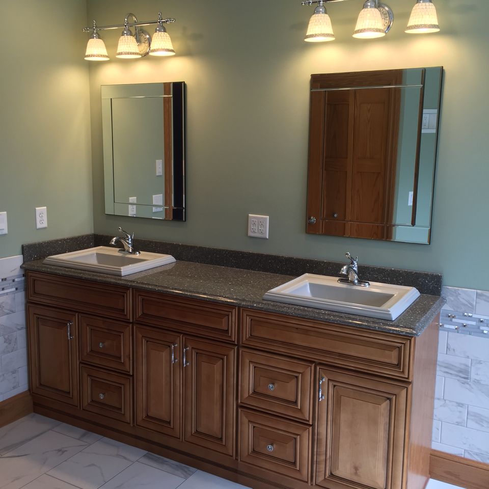 Custom bathroom featuring a double-sink vanity, wood cabinetry, granite countertop, framed mirrors, and modern fixtures.