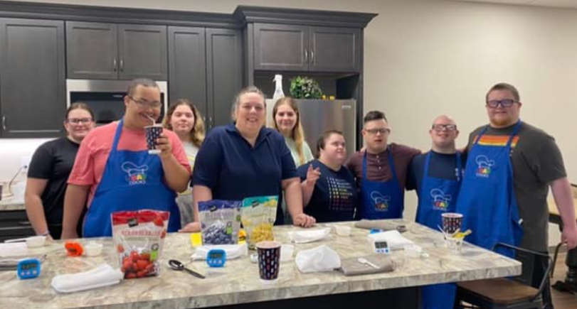 Group of DSAV Cooks participants and instructors smiling together in a teaching kitchen.