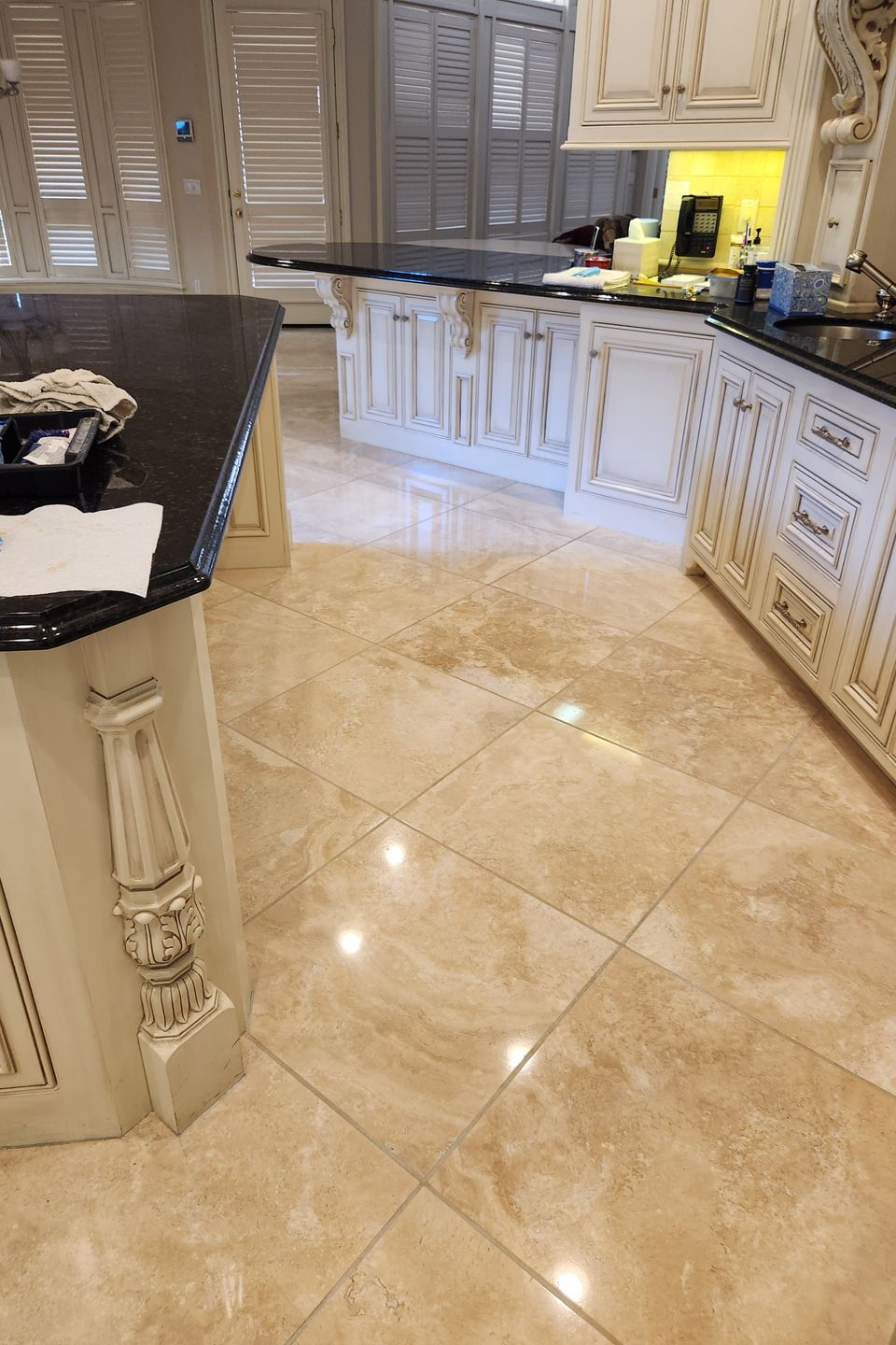 Luxury kitchen with cream cabinetry, dark granite countertops, and polished beige marble tile flooring