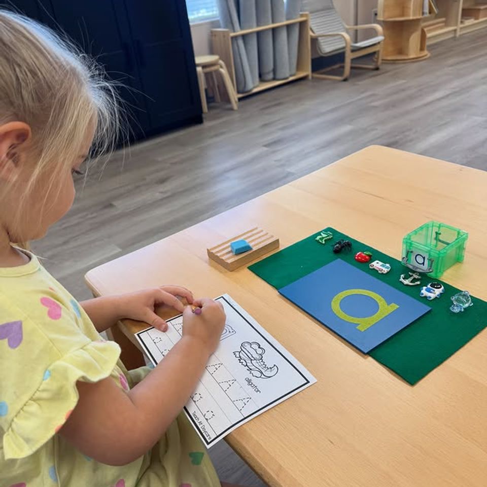 Preschool girl tracing letters on a worksheet during Montessori language work in Palmdale CA