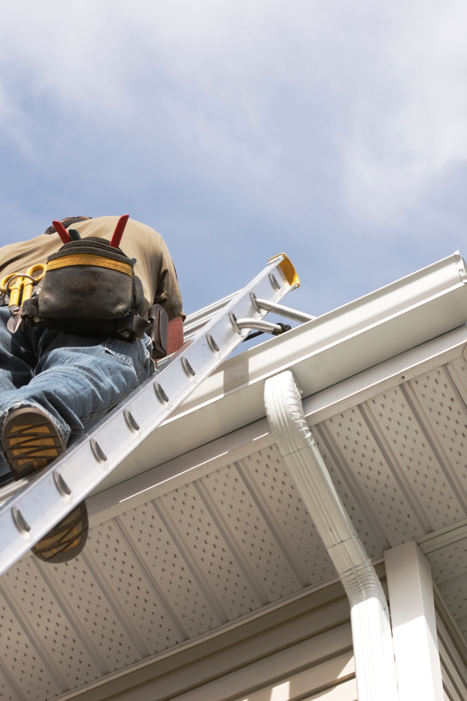 Service technician climbing a ladder to inspect or perform maintenance on a home's roofline, gutters, and exterior.