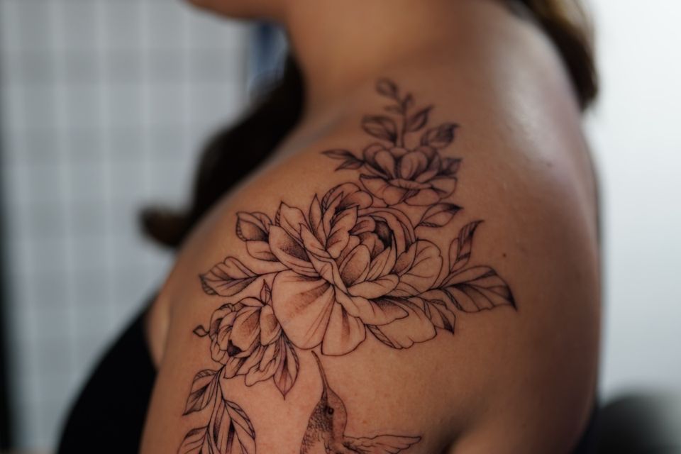 Image of a large shoulder tattoo of a hummingbird feeding on a flower