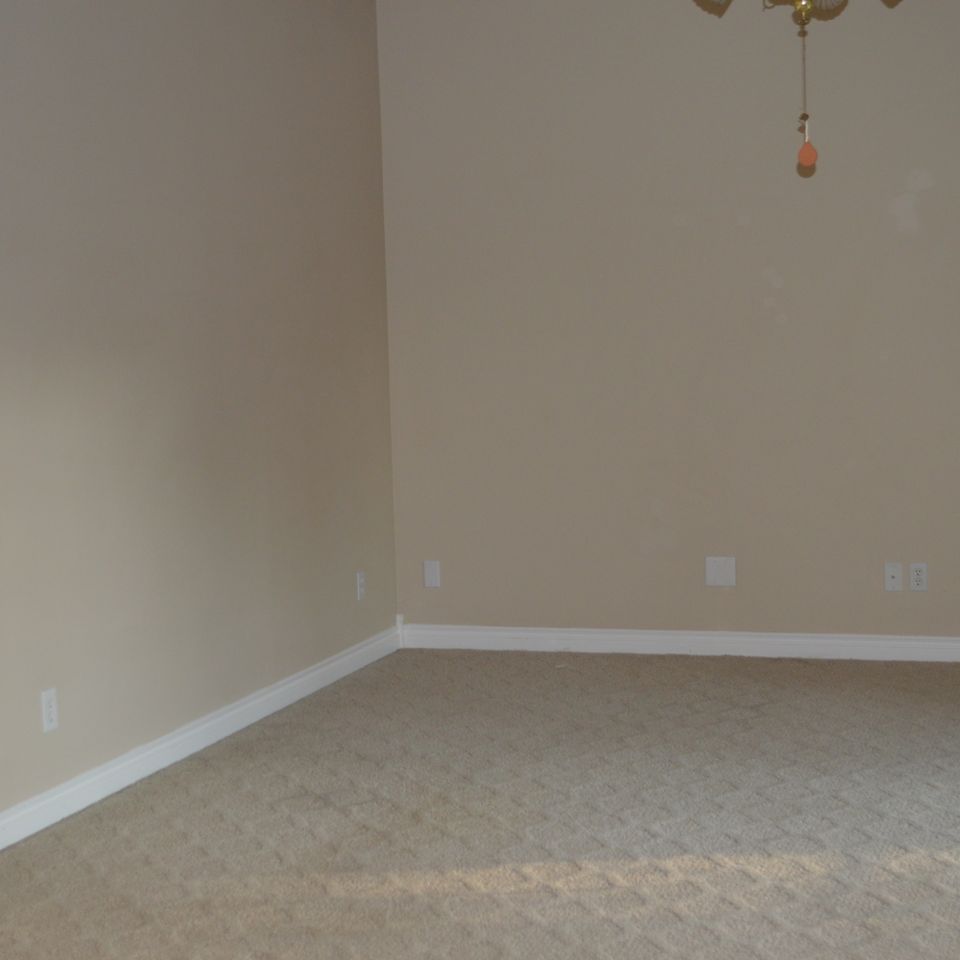 Freshly painted bedroom with new carpet and ceiling fan in a finished custom home