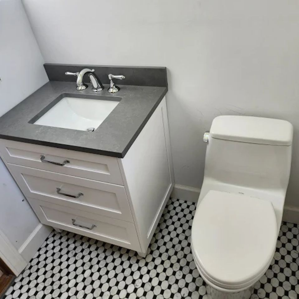 Overview shot of a newly installed white toilet with a sink right next to it done by Taurus Contracting Inc