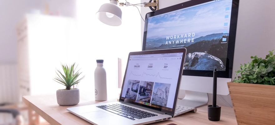 Desk with laptop and monitor showing website
