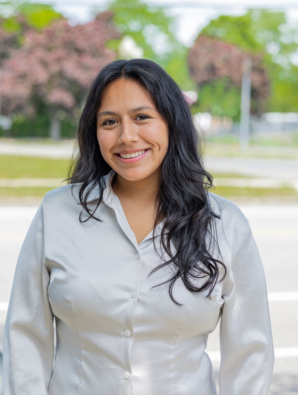 Jenny, owner of Bliss and Bloom Events, smiling outdoors in a white button-down shirt