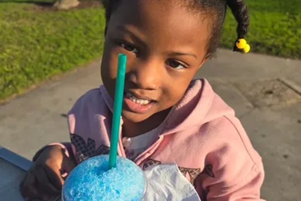 A child smiling with her blue slushie drink