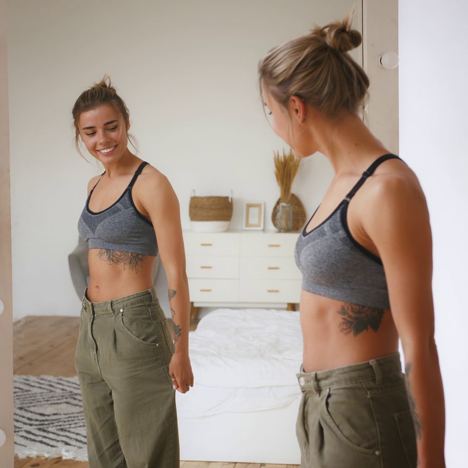 Woman is smiling pulling jeans and showing weight loss standing next to mirror in bedr sbi 351287656