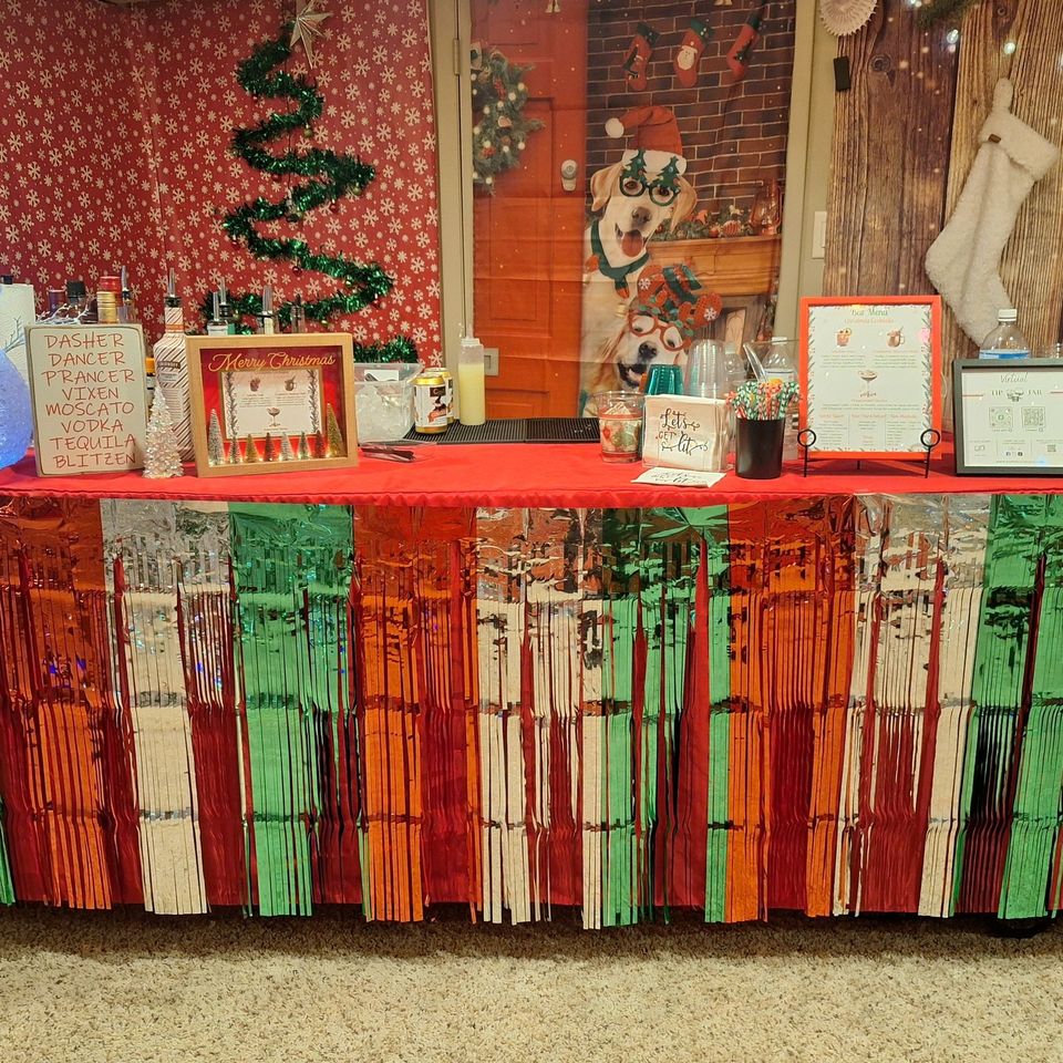 Festive bar setup with Christmas decorations, menu, and drink supplies on a table