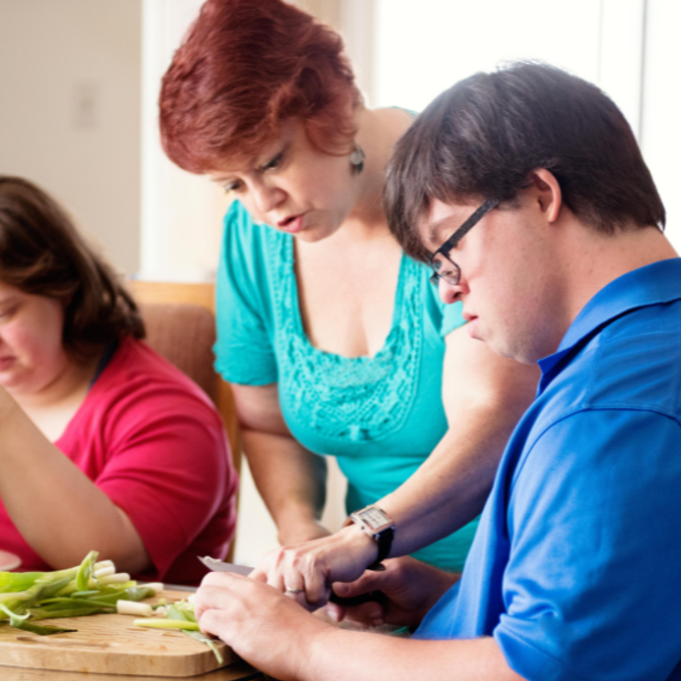 DSAV participant learning food preparation with support from an instructor during a life skills program.