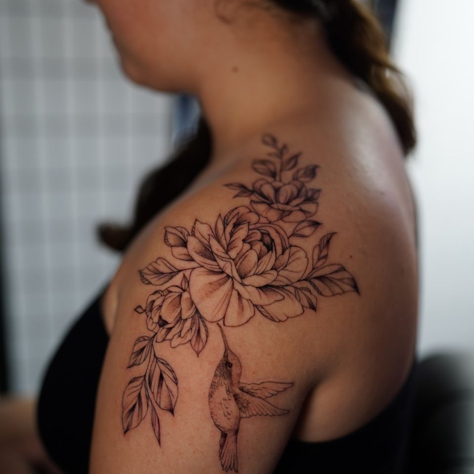 Image of a large shoulder tattoo of a hummingbird feeding on a flower