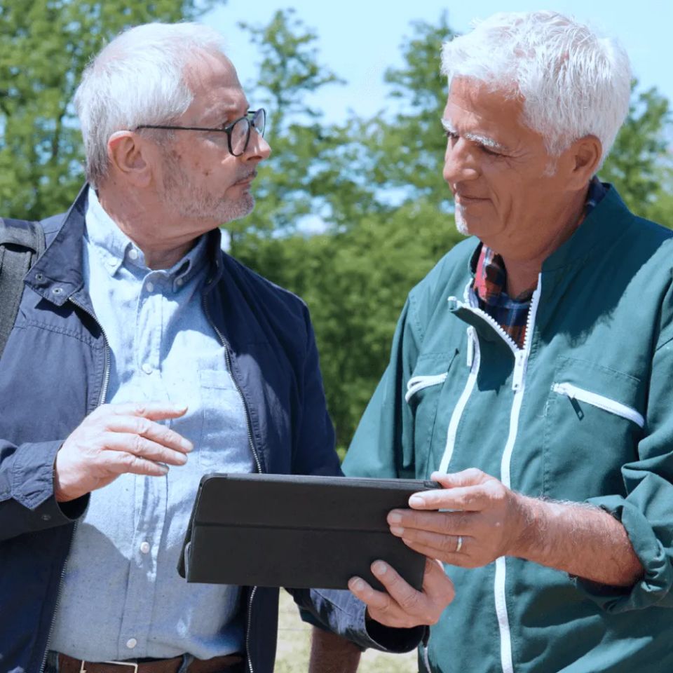 Farmer and insurance agent discussing information on tablet