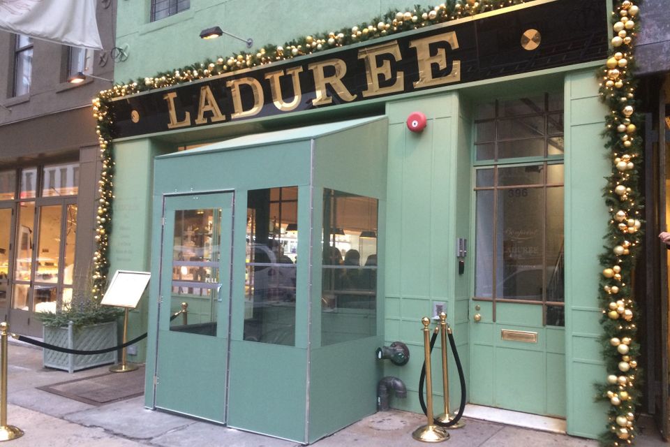 Mint green custom vestibule with glass panels and a double door at the Ladurée storefront, matched to the facade color beneath gold dimensional lettering