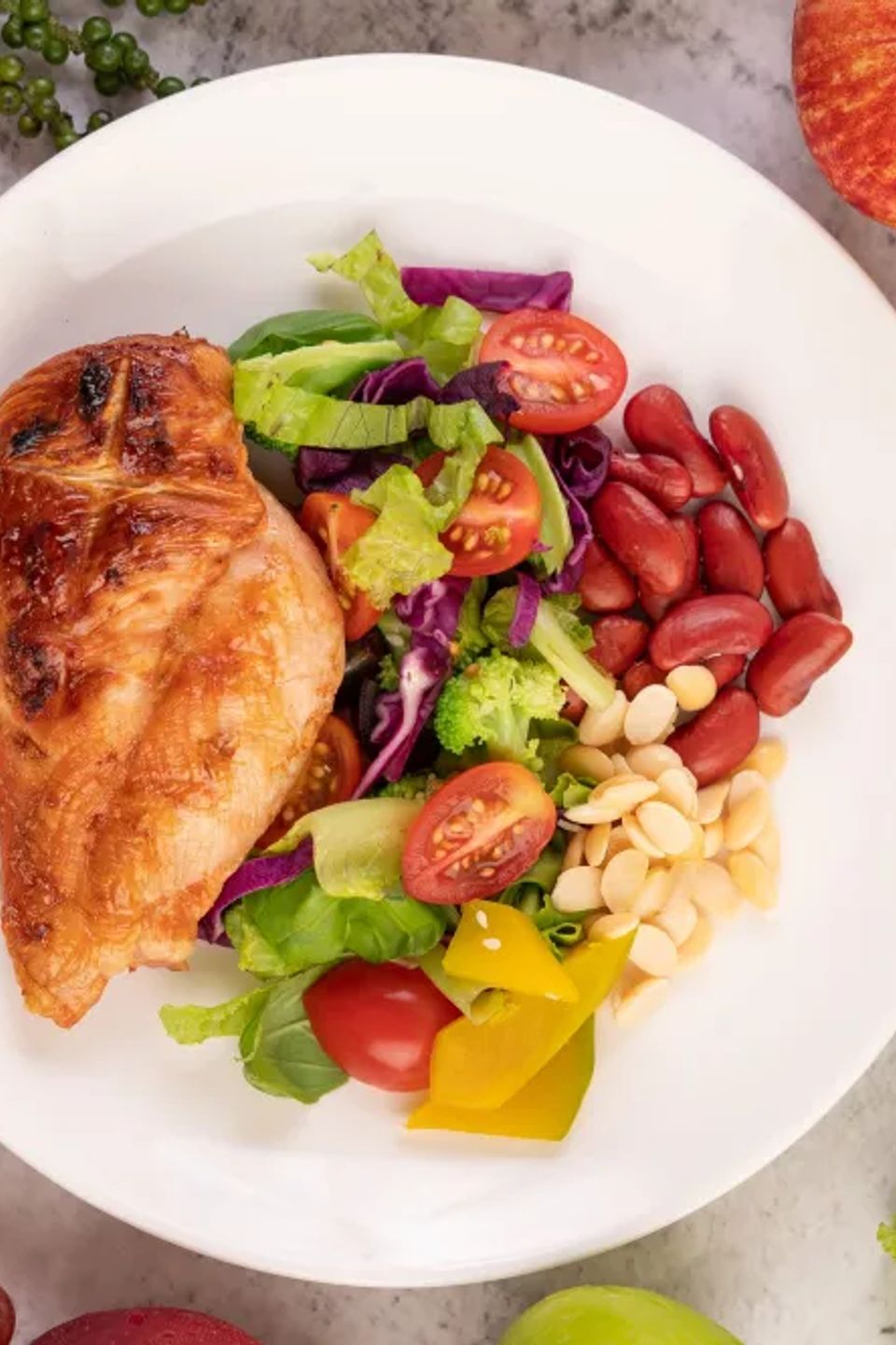 Chicken steak topped with white sesame peas tomatoes broccoli pumpkin white plate
