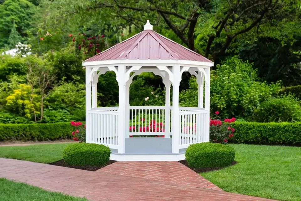 White vinyl gazebo with red metal roof and brick walkway in an East Tennessee garden