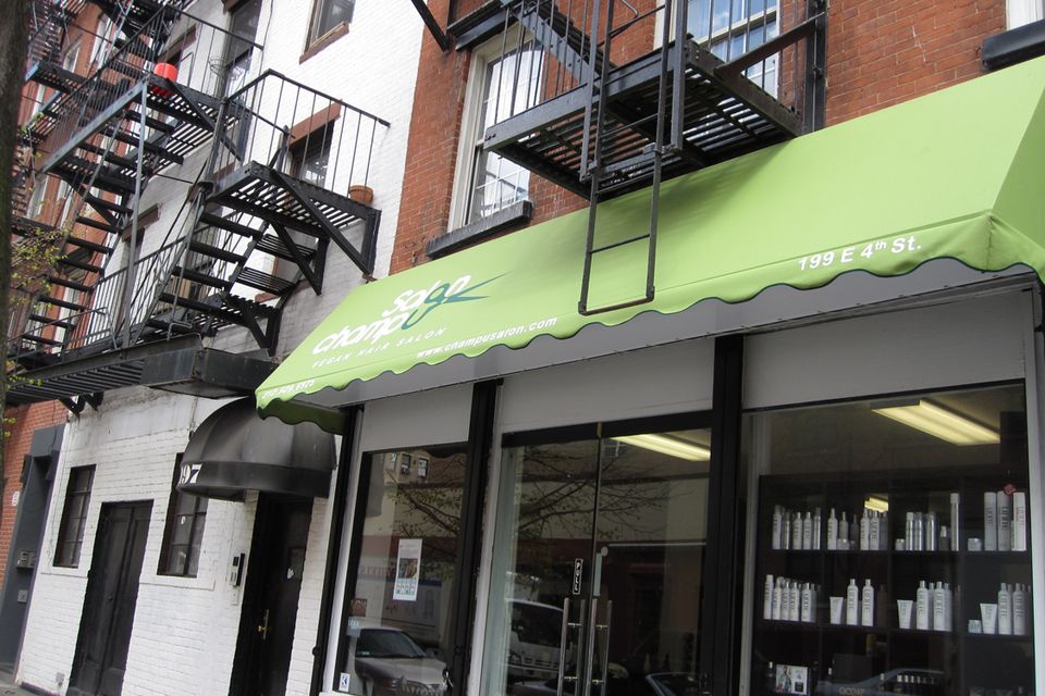 Green storefront awning with printed logo over a salon entrance on East 4th Street in Manhattan