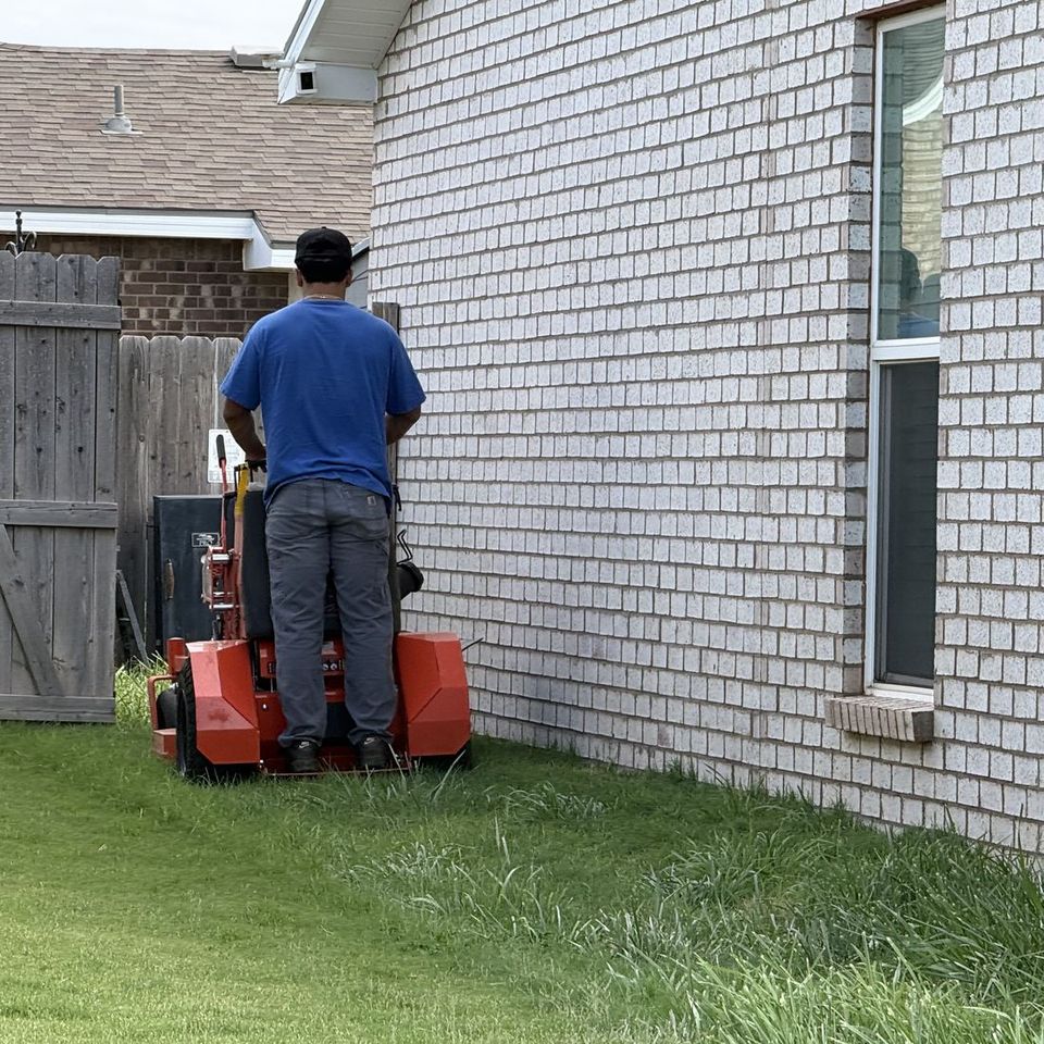 Mowin N Goin crew member mowing a side yard on a stand-on mower