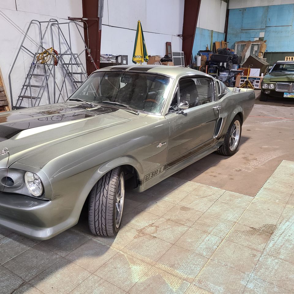 Classic silver car inside a repair shop awaiting professional auto glass service.