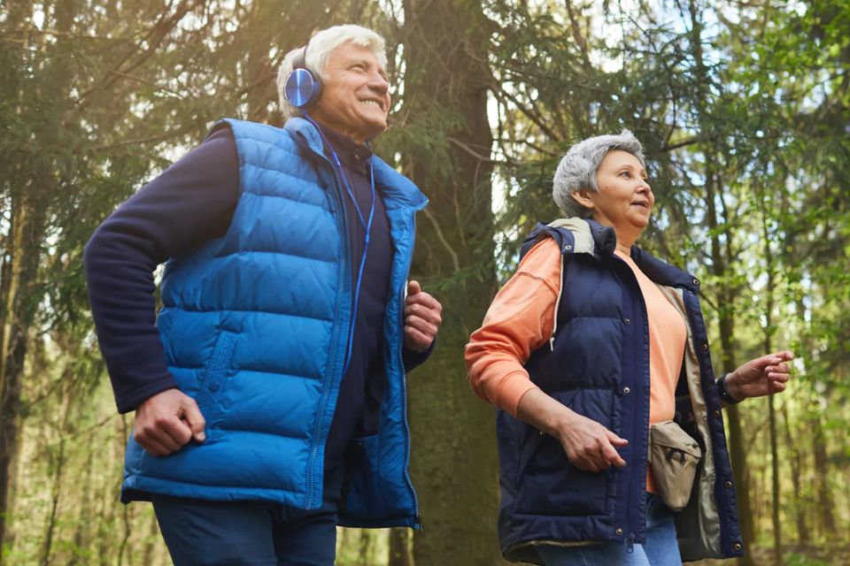 Low angle portrait of active senior couple enjoying morning run in beautiful green forest