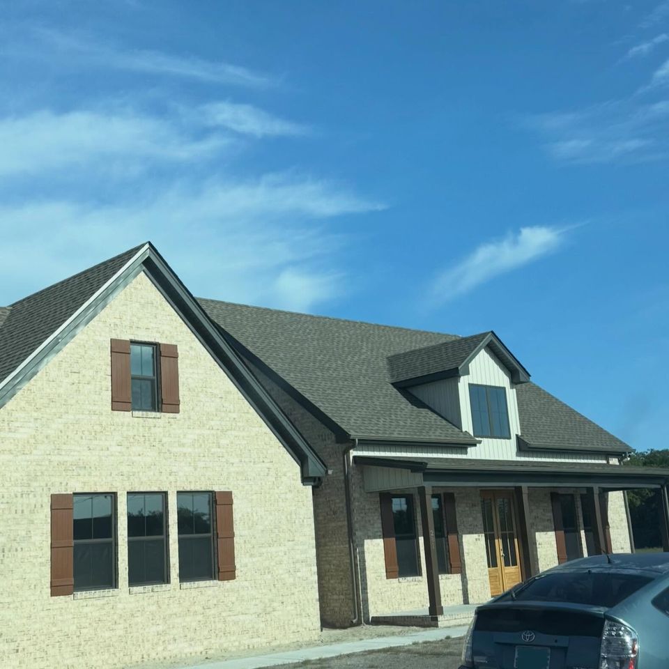 Brick farmhouse style home with tinted windows and brown shutters after house tint in Moyock NC