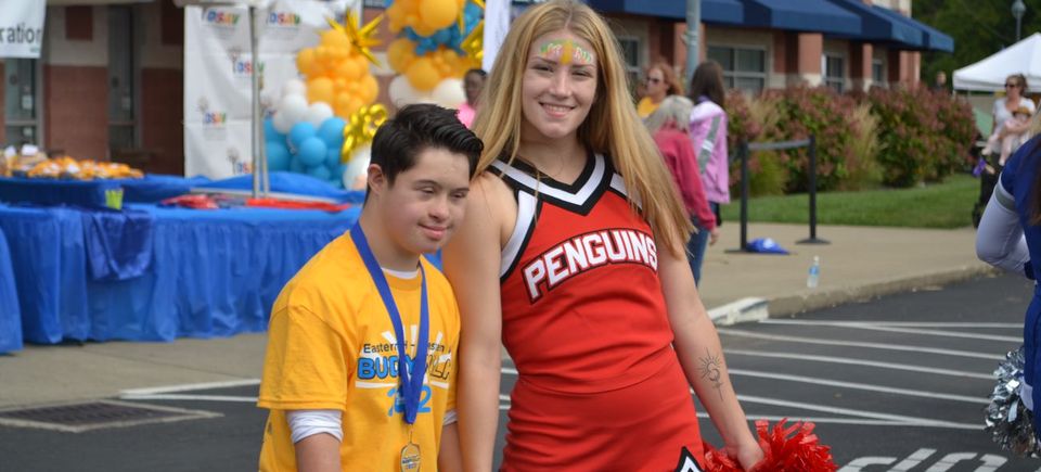 Cheerleader walking alongside a Buddy Walk participant during the DSAV community event.