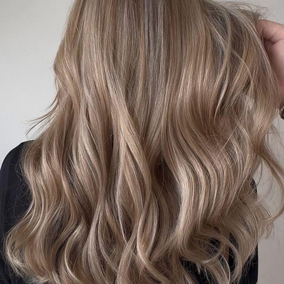 Long wavy sandy blonde hair with blended dimension after color and styling in Columbiana AL