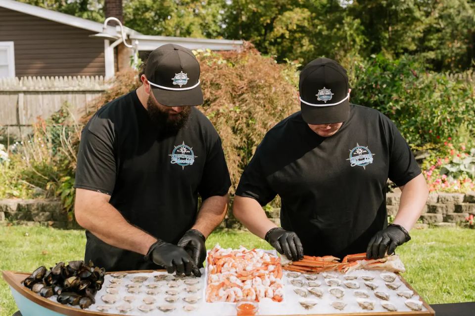 Sean and Mike, the owners of Shore2Shore Shucking working the raw bar, preparing food.
