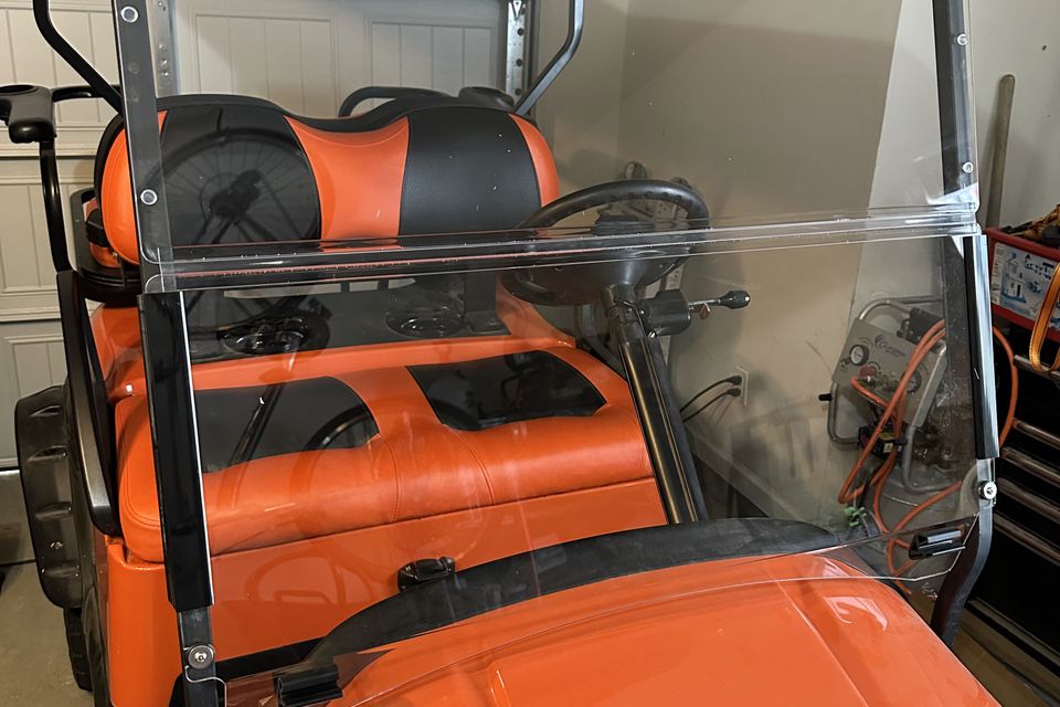 Custom orange golf cart with black and orange leather seats in Madisonville, LA by Neighborhood Golf Carts