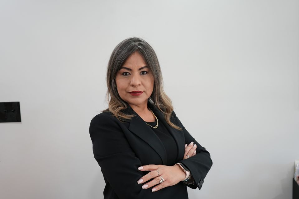 Nancy delgado owner of nadel design in black suit with hands folded