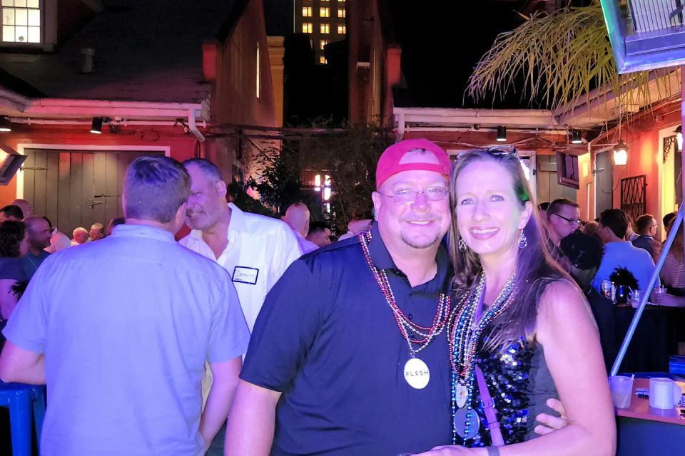 Two patrons with Mardi Gras beads on with the Hotel Monteleone sign in the background at a corporate event on Bourbon Street.