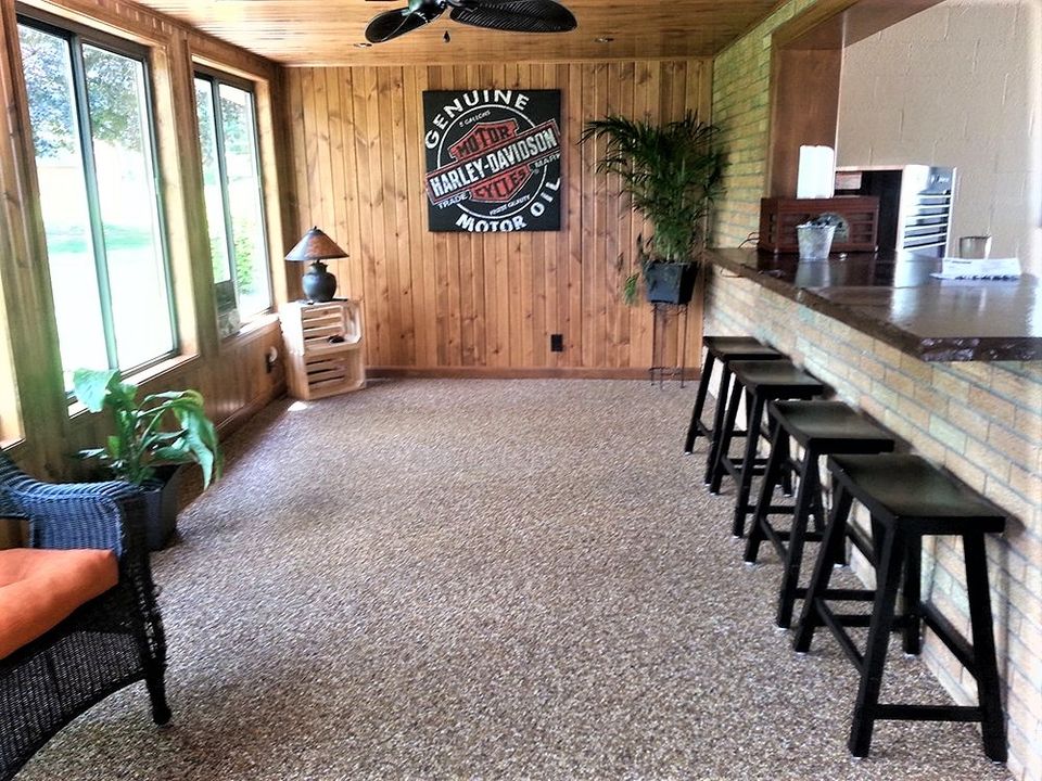 Sunroom featuring decorative stone flooring, wood-paneled walls, large windows, and a bar seating area.
