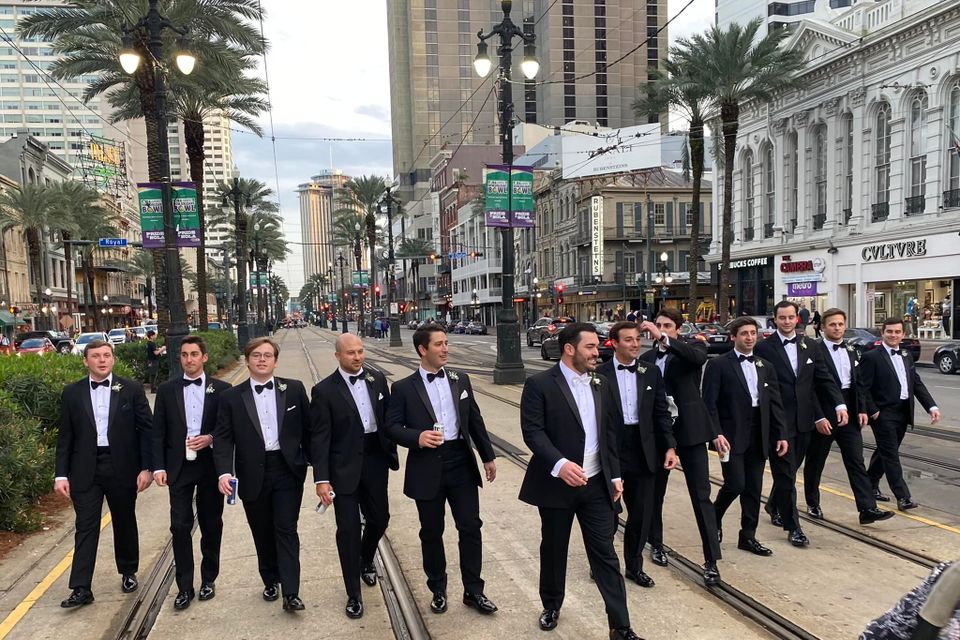 Groomsmen walking down Canal Street in New Orleans wearing classic black tuxedos.