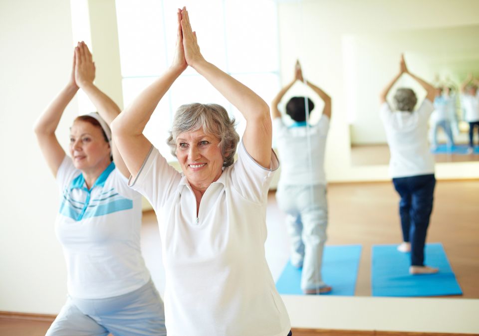 Senior women raising their arms overhead in a group fitness class