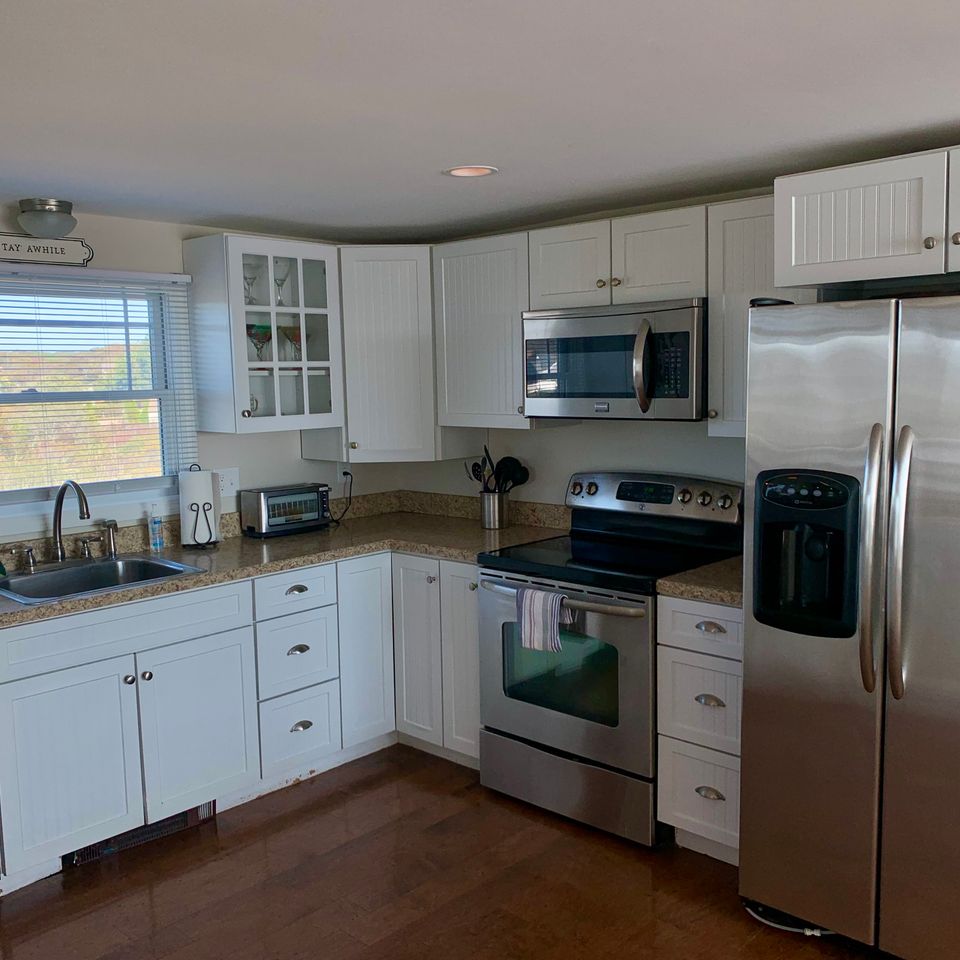 Kitchen with white cabinets, stainless steal appliances .  Refrigerator, Stove, Microwave, dishwasher and big window above sink, looking out to the marsh