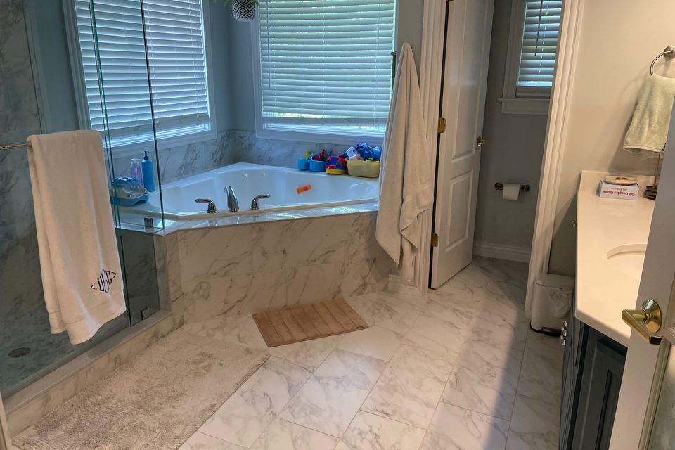 Spotless marble bathroom with corner tub and glass shower after a house cleaning service in Virginia Beach VA