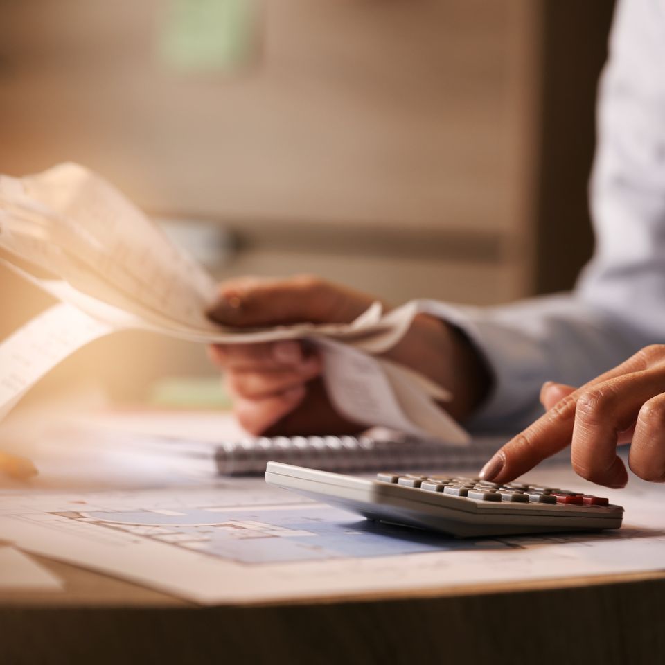 Closeup economist using calculator while going through bills taxes office