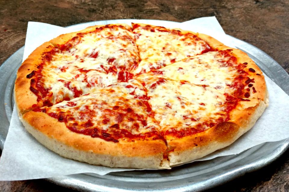 Fresh cheese pizza on a serving tray at Cocca’s Pizza.