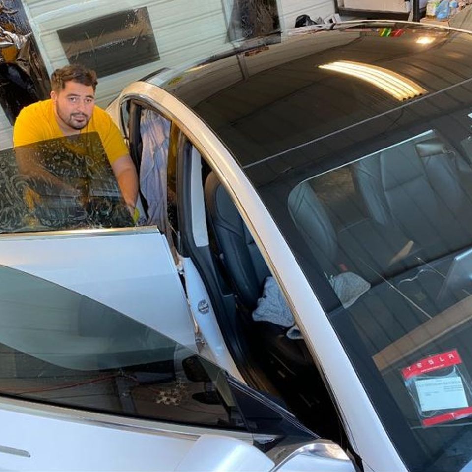 Worker working on white Tesla windows in a shop for gallery