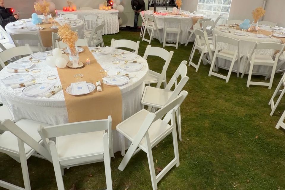 Full event setup with burlap-and-lace round tables and gold balloon backdrop under a tent in the Hamptons