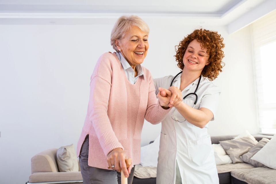 Smiling nurse helping senior lady to walk around the nursing home.