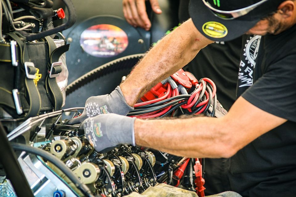 Image of an auto mechanic working inside the valve train area of a motor after he removed the valve cover.