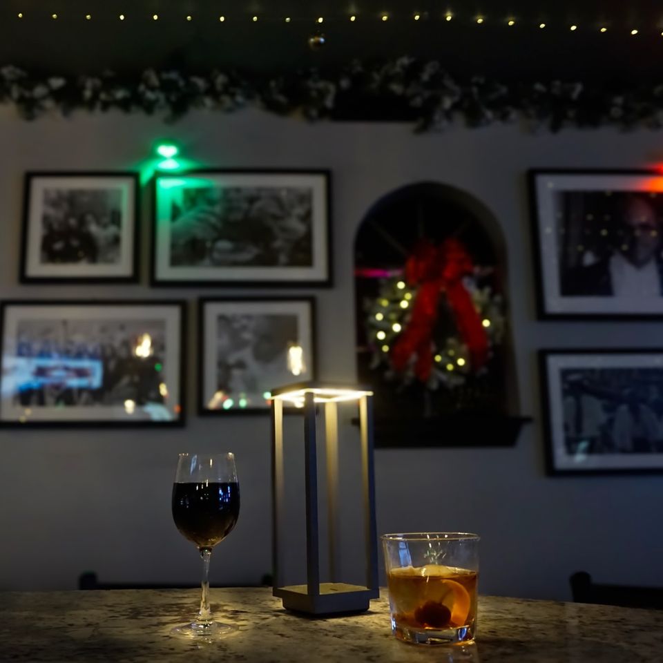 A glass of red wine and a whiskey on a dim lit table at Jilly's