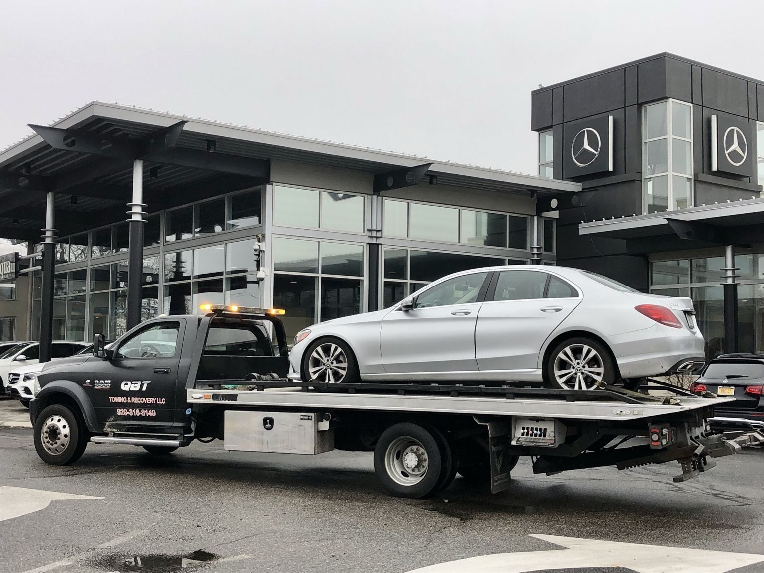 QBT flatbed tow truck carrying a white car