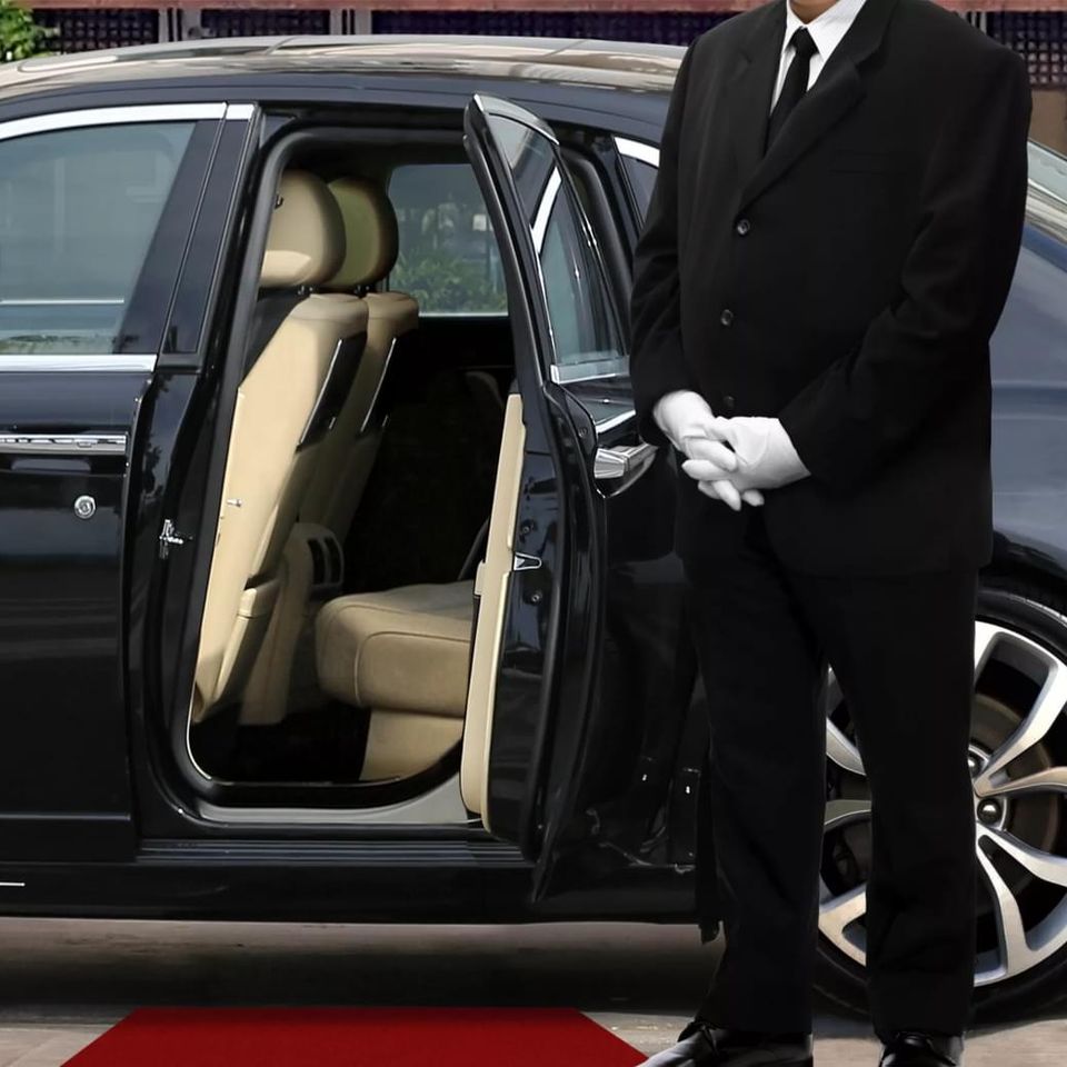A chauffeur opening the door to a car for passengers