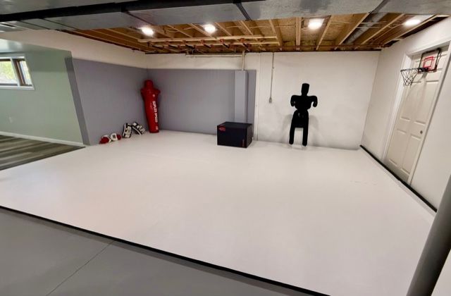 Matted Brazilian Jiu Jitsu training room with red grappling dummy and wall target in Okemos MI