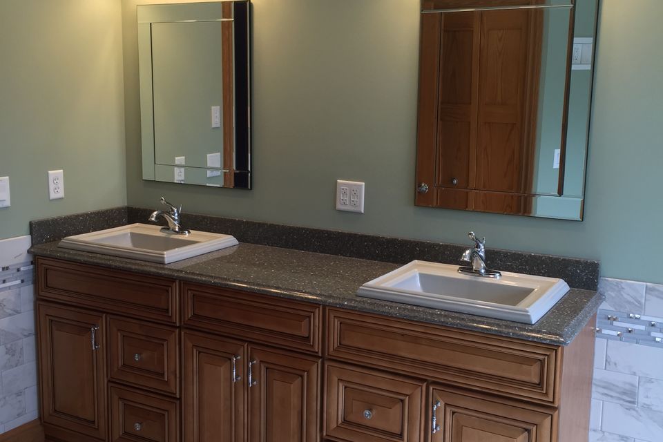 Custom bathroom featuring a double-sink vanity, wood cabinetry, granite countertop, framed mirrors, and modern fixtures.