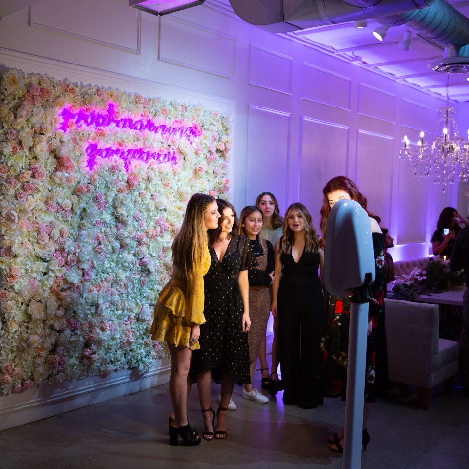 Guests gathered and smiling while using a photo booth at a party.
