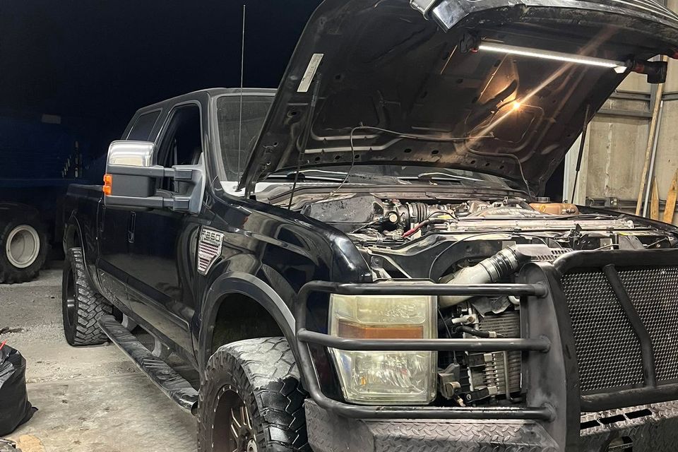 Black Ford F-250 diesel truck with hood open inside repair shop service bay in Arab Alabama